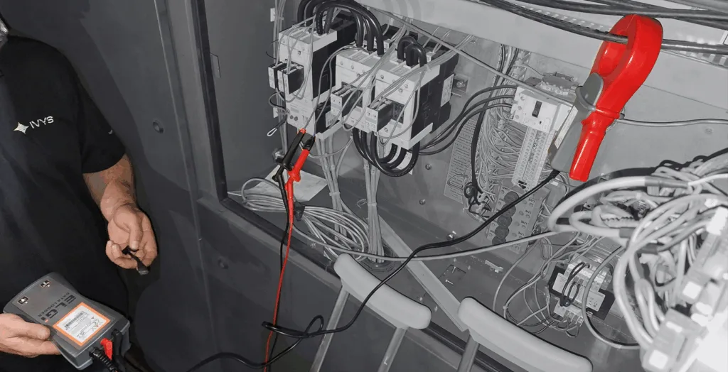 SCADAR prise de mesure noir et blanc Audit énergétique industriel avec l’instrument SCADAR mesurant la consommation électrique dans un panneau de commande pour optimiser les systèmes d’air comprimé. - Industrial energy audit using SCADAR device measuring electrical consumption in a control panel to optimize compressed air systems.