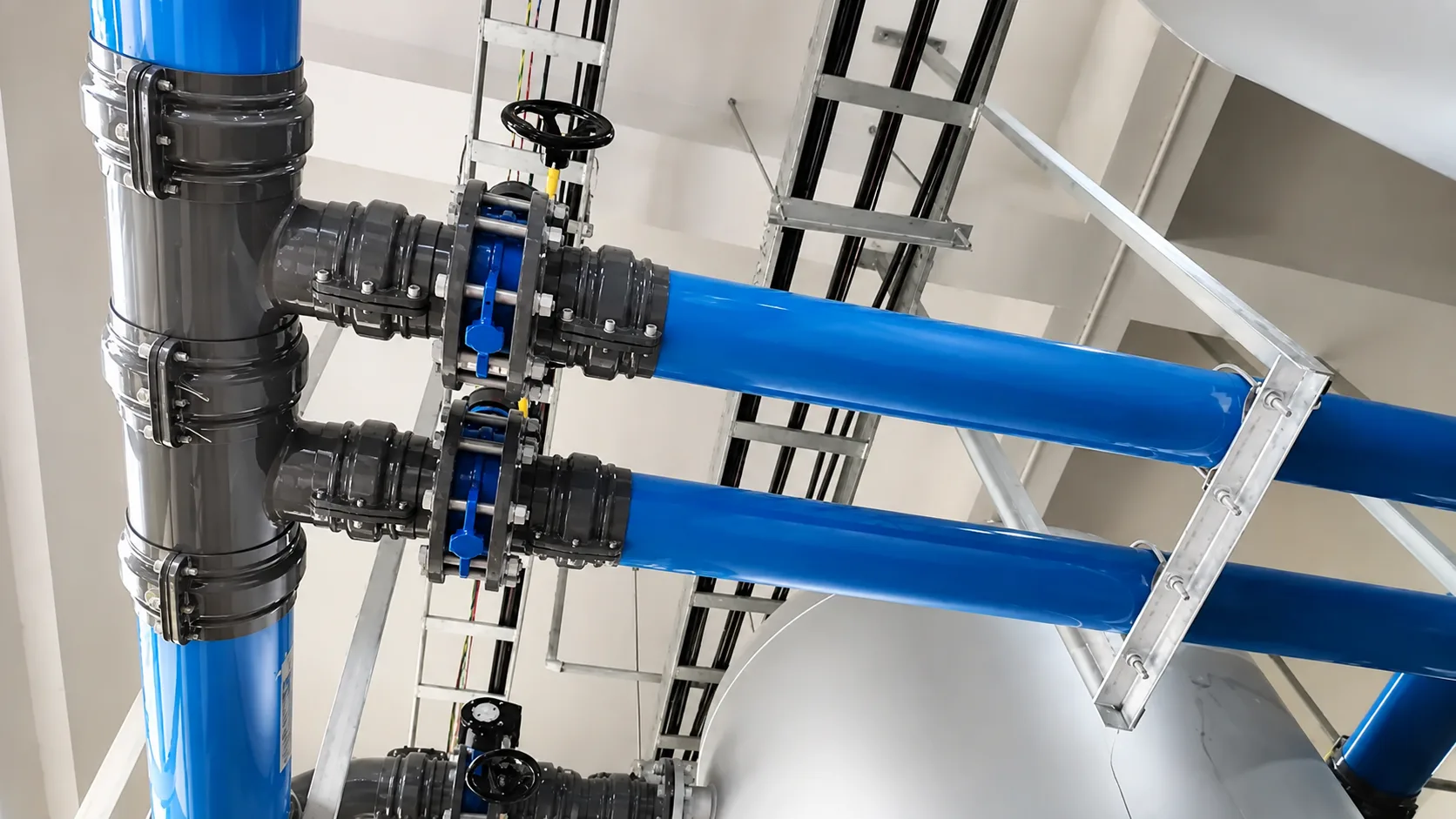 Large-diameter blue aluminum compressed air pipes installed overhead in an industrial facility, connected with modular fittings, isolation valves, and structural supports for reliable air distribution.
